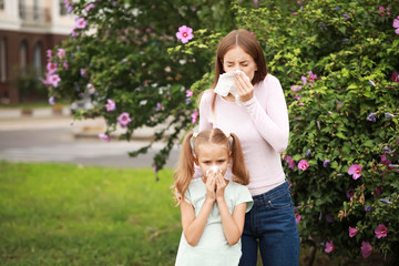 Wall Mural - Young woman and little girl suffering from allergy outdoors