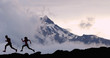 Running fit athletes people trail running with mountain summit background. Man and woman silhouetteon run training outdoors active fit lifestyle.