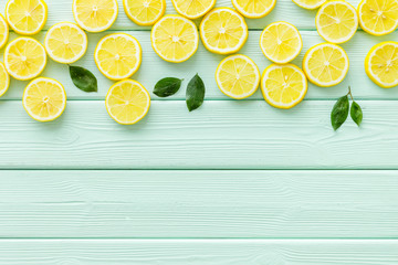 Lemon frame. Sliced citruses and leaves on green wooden background top view copy space