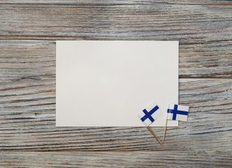 December 6 . Finnish independence day. mini flags on wooden background with white paper sheet