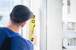 © kurgu128 - the specialist for installing plastic windows checks how smoothly the window has got into the frame with the help of a level tool