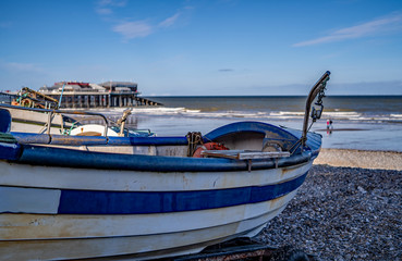 Naklejka na meble 21 Traditional crab fishing boat in focus with an out of focus sea, pier and beach in the background