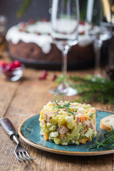 Wall Mural - Traditional Russian salad with cooked vegetables with mayonnaise in a plate. Wooden background.