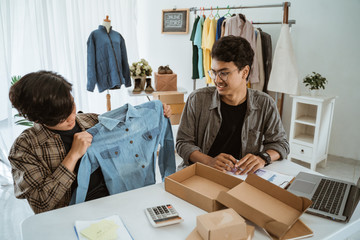 fashion seller discussing product for sale in his office with partner together