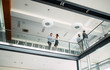 © NDABCREATIVITY - Modern business people walking on stairs in glass hall in office
