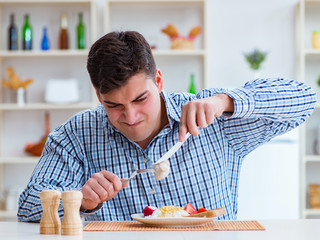 Wall Mural - Man eating tasteless food at home for lunch