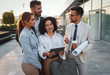 © Zoran Zeremski - Group of coworkers standing outside in front of office buildings discuss about business plan and looking at tablet.
