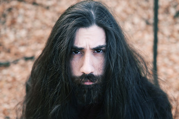 atmospheric autumn outdoor portrait of young man wearing long hair, beard and moustache