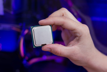 Fototapete - Hand holds a modern processor. Computer with RGB illumination in background. Close-up.
