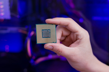 Fototapete - Back of a computer processor in hand. RGB light in background. Close-up.
