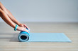 © Kalim - Young woman rolling yoga mat at home
