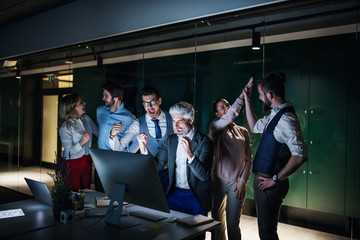 A group of business people with computer in an office, expressing excitement.