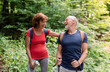 © Halfpoint - Senior tourist couple with backpacks on a walk in forest in nature.