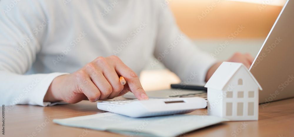 close up young man hand press on calculator to check and summary expense of home loan mortgage for refinance plan , people lifestyle concept - obrazy, fototapety, plakaty 