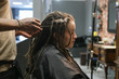 African master hairdresser  making dreadlocks for young woman in hair salon