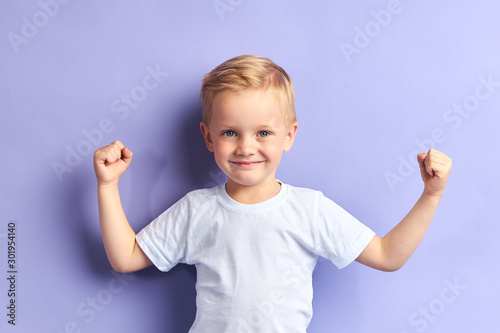 Cuadros en Lienzo Winner kid isolated over purple background, show how powerful he is