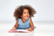© Syda Productions - childhood, school and education concept - happy smiling little african american girl reading book over grey background