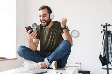 Sticker - Image of young man listening music with headphones and using cellphone