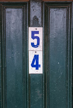 The Number 54 Is Attached To A Green Pitted Wooden Door