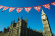 Vintage British Union Jack flag bunting hanging in front of the Houses of Parliament at Westminster on a bright sunny day in London, UK