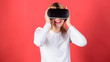 © be free - Portrait of woman in a white blouse with virtual reality glasses on head isolated on red background. Happy woman exploring augmented world, interacting with digital interface.