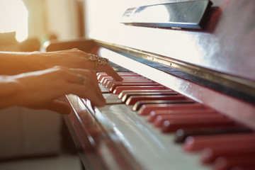 Female hands wearing jewellery rings playing on Pink piano keyboard