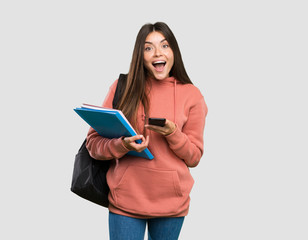 Young student woman holding notebooks surprised and sending a message over isolated grey background