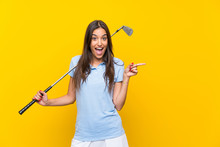 Young Golfer Woman Over Isolated Yellow Wall Surprised And Pointing Finger To The Side