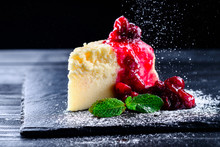 Cherry Cheesecake On A Black Background With Reflection And Flying Icing Sugar