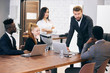 © alfa27 - Caucasian man leader of multi-ethnic group stand near table while everyone listening to him. Business, teamwork concept. Young caucasian boss in tuxedo
