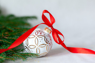 Wall Mural - Christmas holidays composition with white ball and red ribbon on light background with copy space