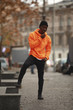 Handsome African man model wearing bright orange hoodie in city