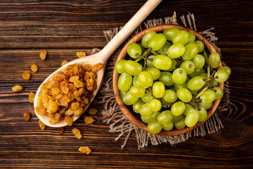 Wall Mural - Raisin and green grape on dark wooden background.