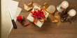 christmas gift box tied with red and golden bow over a wooden table with candles. Horizontal composition with copy space below.