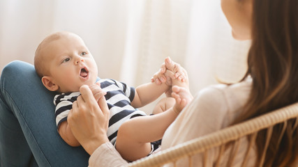 Adorable newborn baby cooing while lying on mother's lap