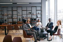 Internatonal group of business partners discuss future successful deal in modern office, wearing formal wear