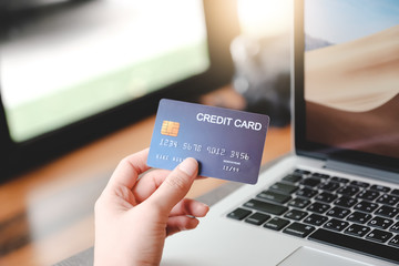 A woman is going to pay for the goods in the internet using credit card and laptop computer. Online shopping concept.