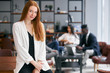© alfa27 - Young caucasian redhaired businesswoman dressed in white blazer stand cutely looking at camera in office environment