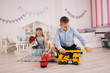 beautiful happy caucasian children playing in their room, boy playing with cars, girl playing with dolls