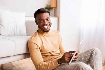 Poster - Black Guy Using Tablet Sitting On Floor At Home