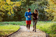 © Dusan Petkovic - Full length of cute caucasian couple in sportswear walking on trail in woods, smiling and talking