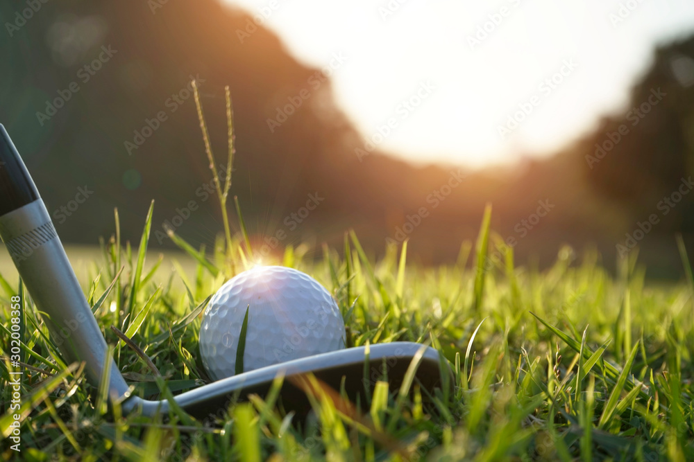 Blurred golf club and golf ball close up in grass field with sunset. Golf ball close up in golf coures at Thailand - obrazy, fototapety, plakaty 