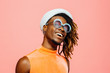 © Carlos David - Portrait of a happy young man with sunglasses and cap laughing, isolated on pink