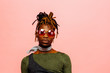 © Carlos David - Portrait of a serious young man in green with dreadlocks and red sunglasses, isolated on pink