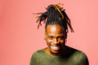 Portrait of a happy, smiling  young man in with cool dreadlocks hairstyle looking at camera, isolated on pink.