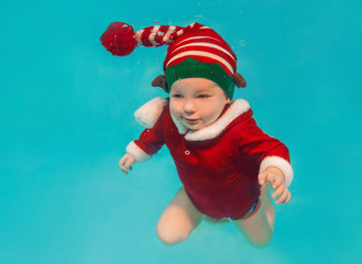 Caucasian infant underwater in new year and christmas suit in the swimming pool