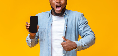 Poster - African guy demonstrating blank smartphone and gesturing thumb up