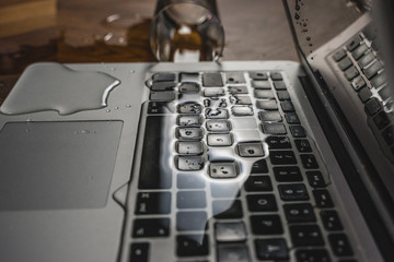 Glass of spilled water on laptop