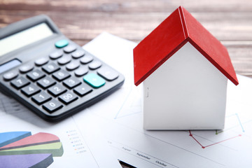 Wooden house model with financial papers and calculator