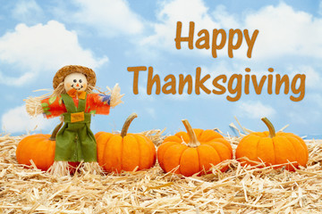 Wall Mural - Happy Thanksgiving message with scarecrow and orange pumpkins on straw hay